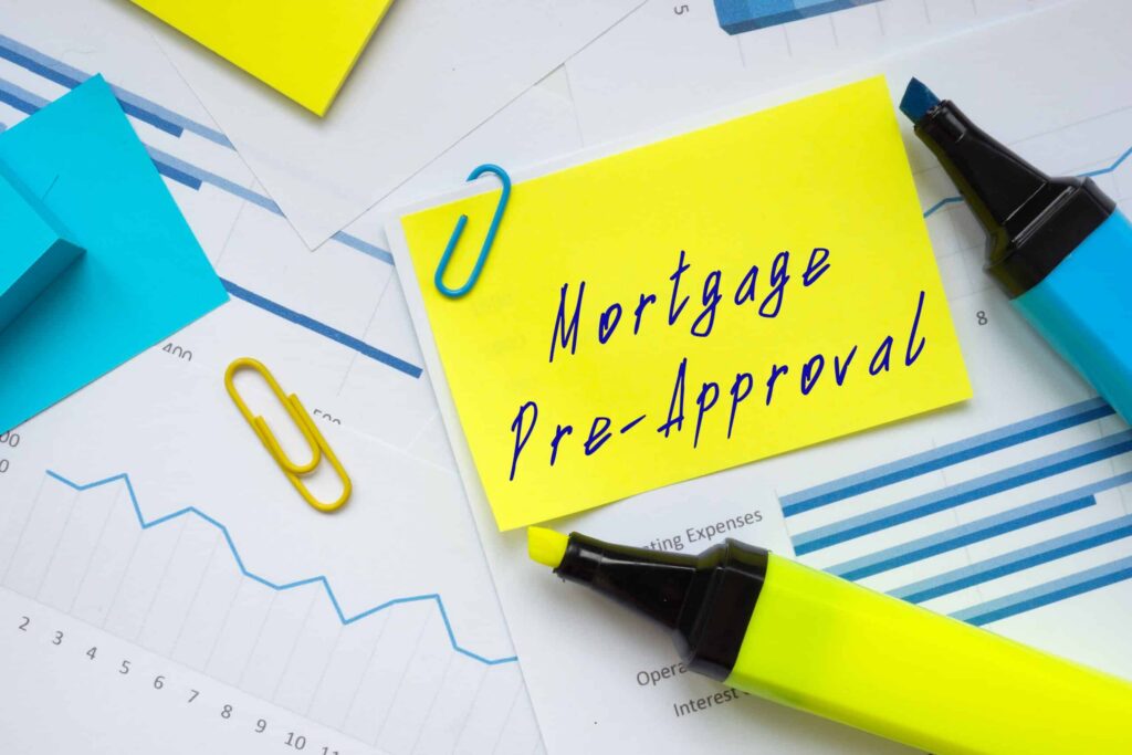 Yellow sticky note with 'Mortgage Pre-Approval' handwritten, surrounded by blue/yellow office supplies on a financial chart backdrop