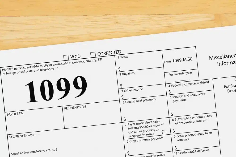Close-up of a Form 1099-MISC with a large '1099' heading and labeled boxes on a wooden desk surface.